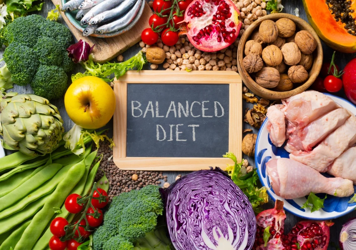 voće, povrće, meso, orašasti plodovi, riba, sve lepo poređano da uokviri natpris na maloj tabli koji glasi - izbalansirana ishrana (balanced diet)