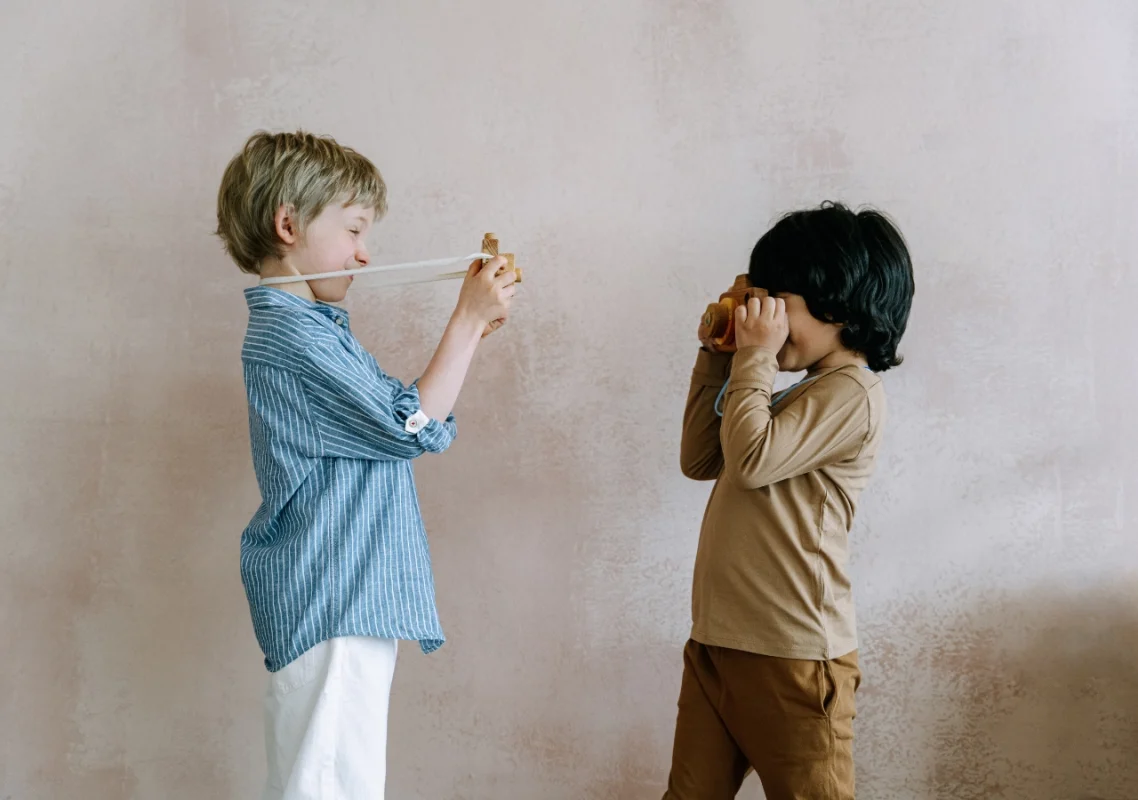 dva dečaka, jedan u plavoj košulji a drugi u braon kompletiću, fotografišu jedan drugog fotoaparatima za decu